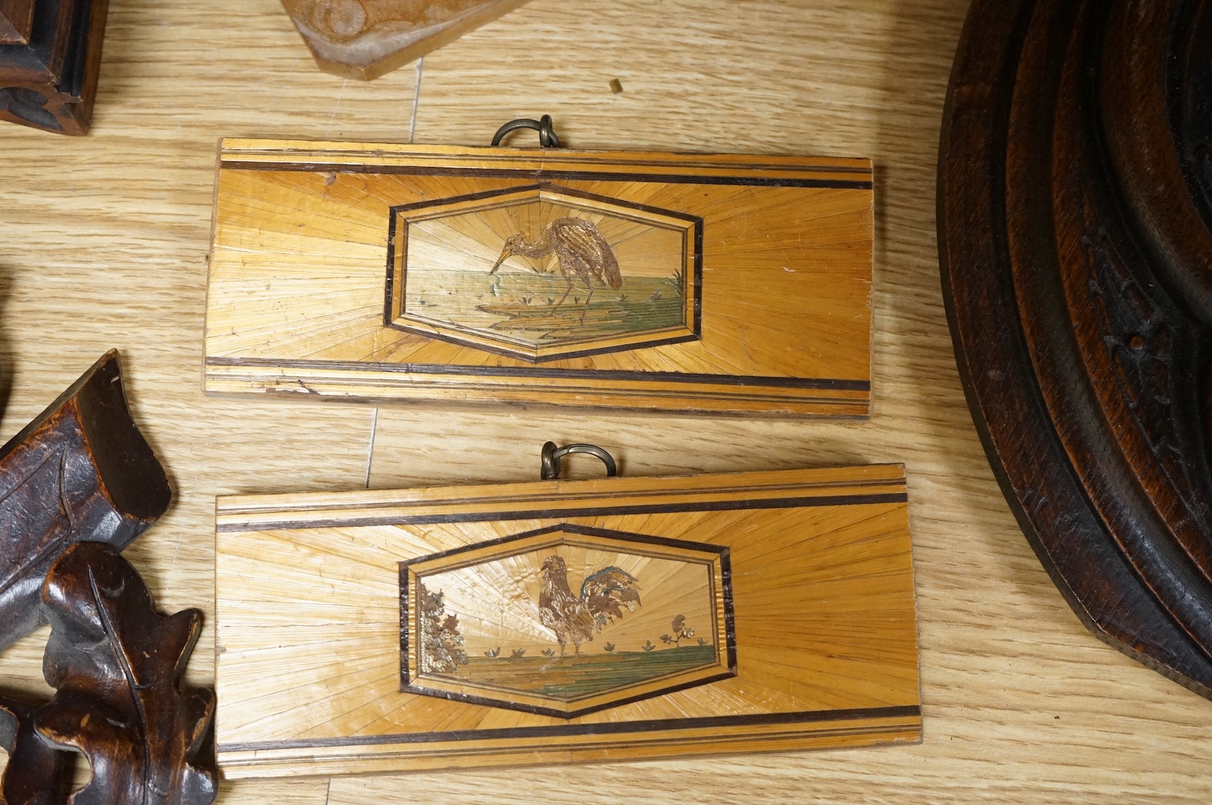 A pair of Gothic revival oak wall plaques, a Black Forest carved barometer, a Virgin and child figure, an IHS embroidered panel, two straw worked panels and a carved finial, barometer 47cm high